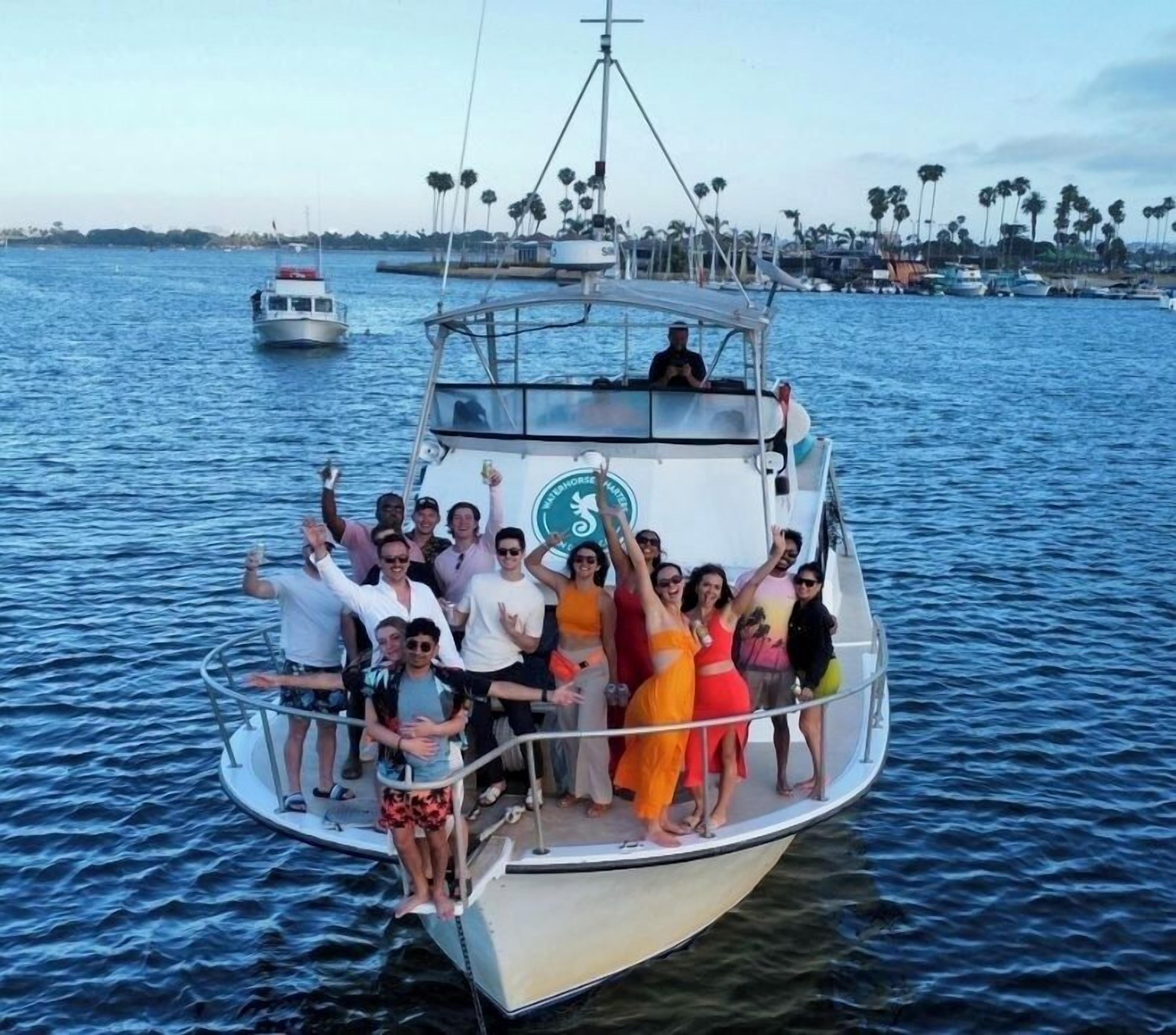 A group of people on a boat with a clear view of the water and palm trees in the background.