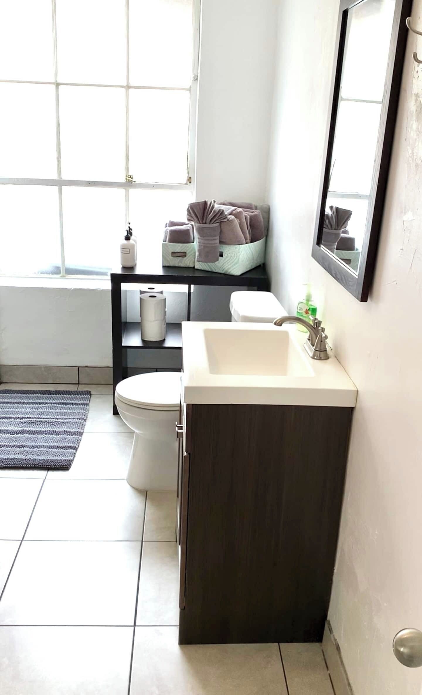 Ein kleines Badezimmer mit Toilette, Waschbecken und Fenster.