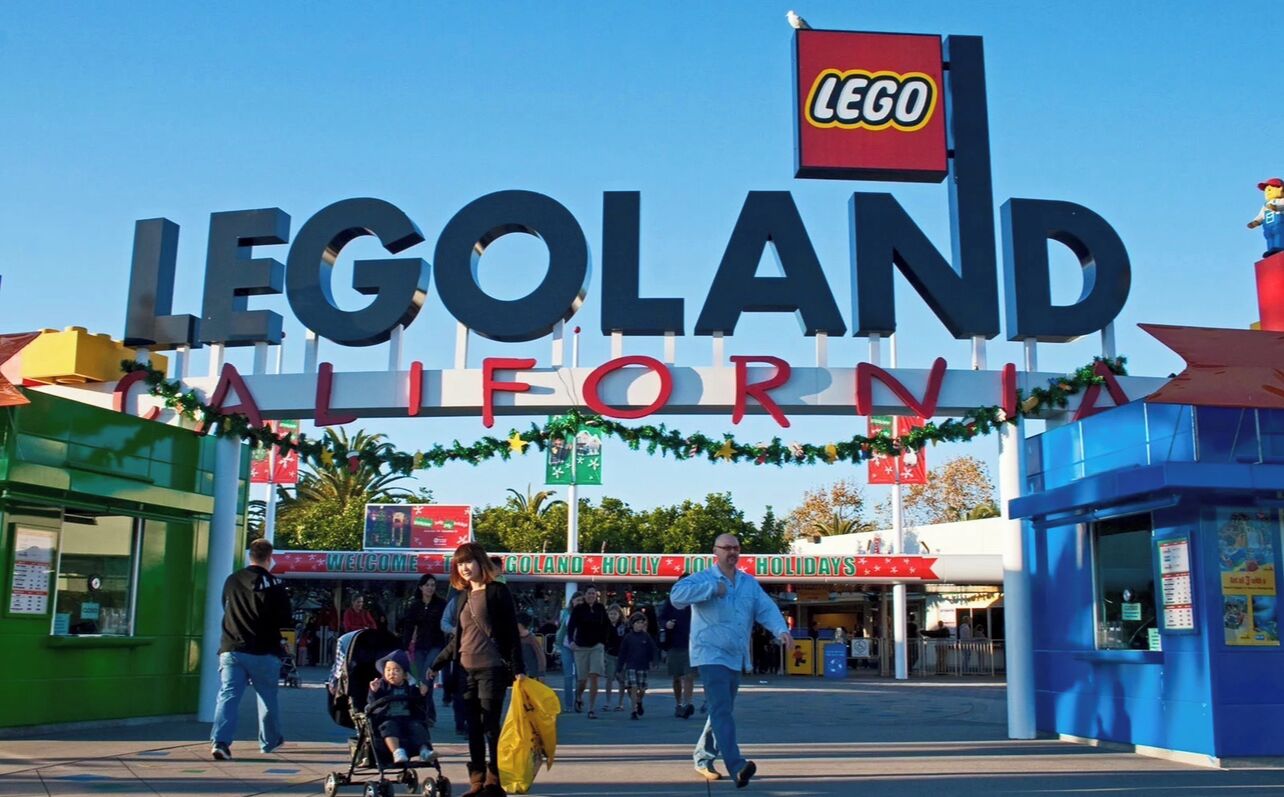 The entrance to LEGOLAND California with a large sign and festive decorations.