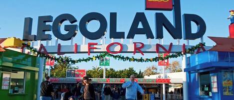 The entrance to LEGOLAND California with a large sign and festive decorations.
