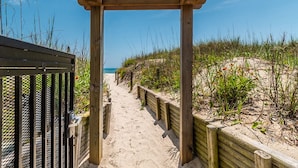 Ein hölzerner Weg führt zu einem Strand mit freiem Blick auf das Meer.