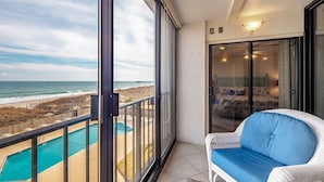 Ein Balkon mit Blick auf den Ozean und einen Swimmingpool.