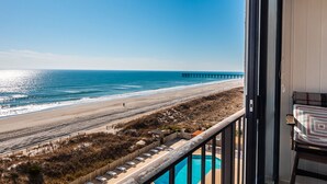 A balcony with a view of the beach, a pier, and a swimming pool. - Modern 2BR/2BA condo unit w/ community pool and oceanfront view (Wrightsville Beach)