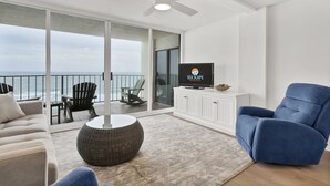 A spacious living room with a large TV, comfortable seating, and a view of the ocean. - Savor ocean views in this 2BR/2Ba condo w/community pool (Wrightsville Beach)