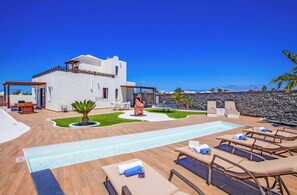 A modern villa with a swimming pool, outdoor seating, and a view of the sea. - Villa Esmeralda - Four Bedroom Villa, Sleeps 8 (Montaña Roja)