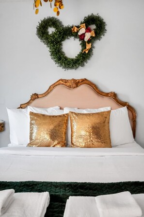Ein Bett mit dekorativer Kopfteil, weißer Bettwäsche und einem herzförmigen Wandkranz.