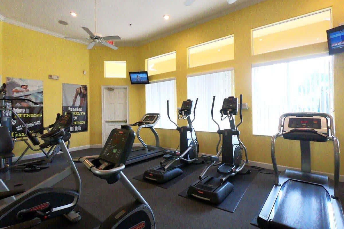 Un gimnasio con cintas de correr, elípticas y bicicletas estáticas.
