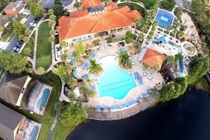An aerial view of a resort with a large central pool, multiple smaller pools, and a variety of outdoor seating areas.