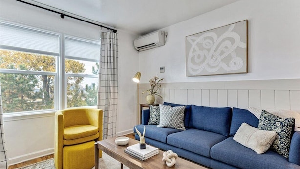 A modern living room with a blue sofa, a yellow armchair, and a wooden coffee table.