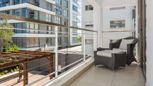A balcony with a wicker chair and a wooden pergola. - Luxe 2-Bed in Trendy Green Point , Pool Views (Cape Town)