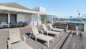 A rooftop deck with lounge chairs, a pool, and a dining area. - Luxe 2-Bed in Trendy Green Point , Pool Views (Cape Town)