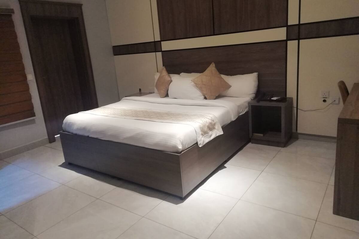 A modern bedroom with a large bed, a nightstand, and a wooden headboard.