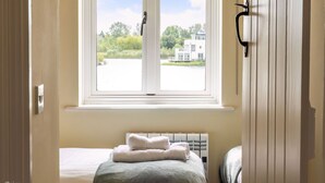 Ein Hotelzimmer mit einem Bett, einem Fenster mit Blick auf Grünflächen und ein Gebäude, sowie einem Heizkörper.