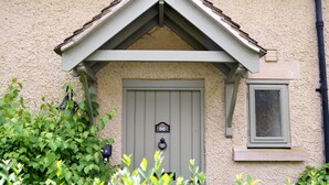 Ein Haus mit einer grauen Tür, die mit der Nummer 66 gekennzeichnet ist, einem kleinen Fenster und einem Briefkasten.