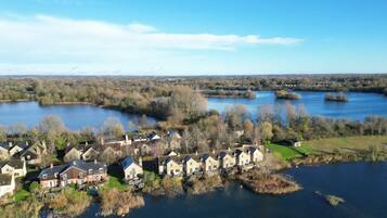 Een woonwijk met huizen langs een rivier, omringd door bomen en open velden.