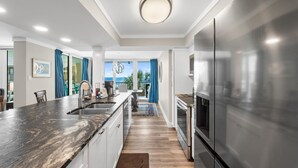A modern kitchen with a large island, stainless steel appliances, and a view to the outdoors.