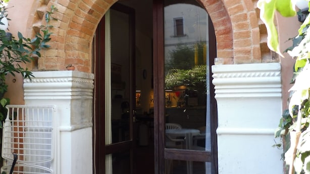 A brick archway leading to a door, with a white bench and a table outside. - STUDIO APARTMENT WITH SMALL GARDEN (Lido)