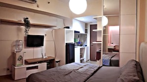 Une chambre à coucher moderne avec un lit, une télévision, une armoire et un miroir.