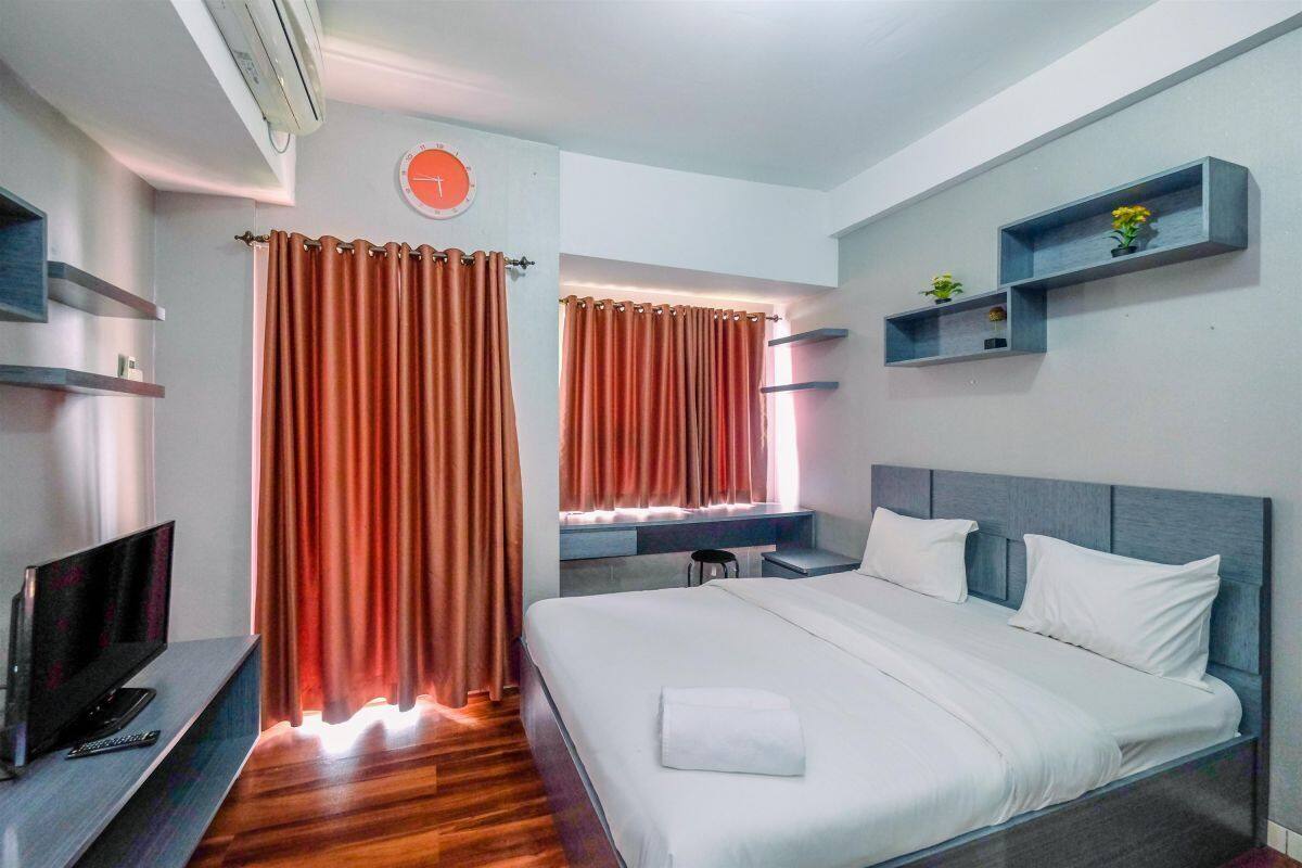 Ein Hotelzimmer mit Bett, Fernseher, Schreibtisch und einem Fenster mit Vorhängen.