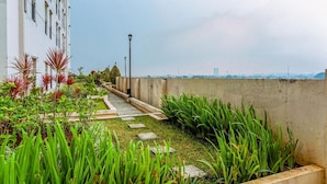 Un jardin sur le toit, agrémenté d’un sentier, de verdure et offrant une vue sur le panorama urbain.