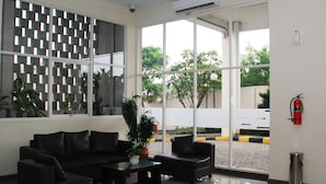 Un hall d’entrée moderne avec un canapé en cuir noir, une table basse en verre et une plante en pot.