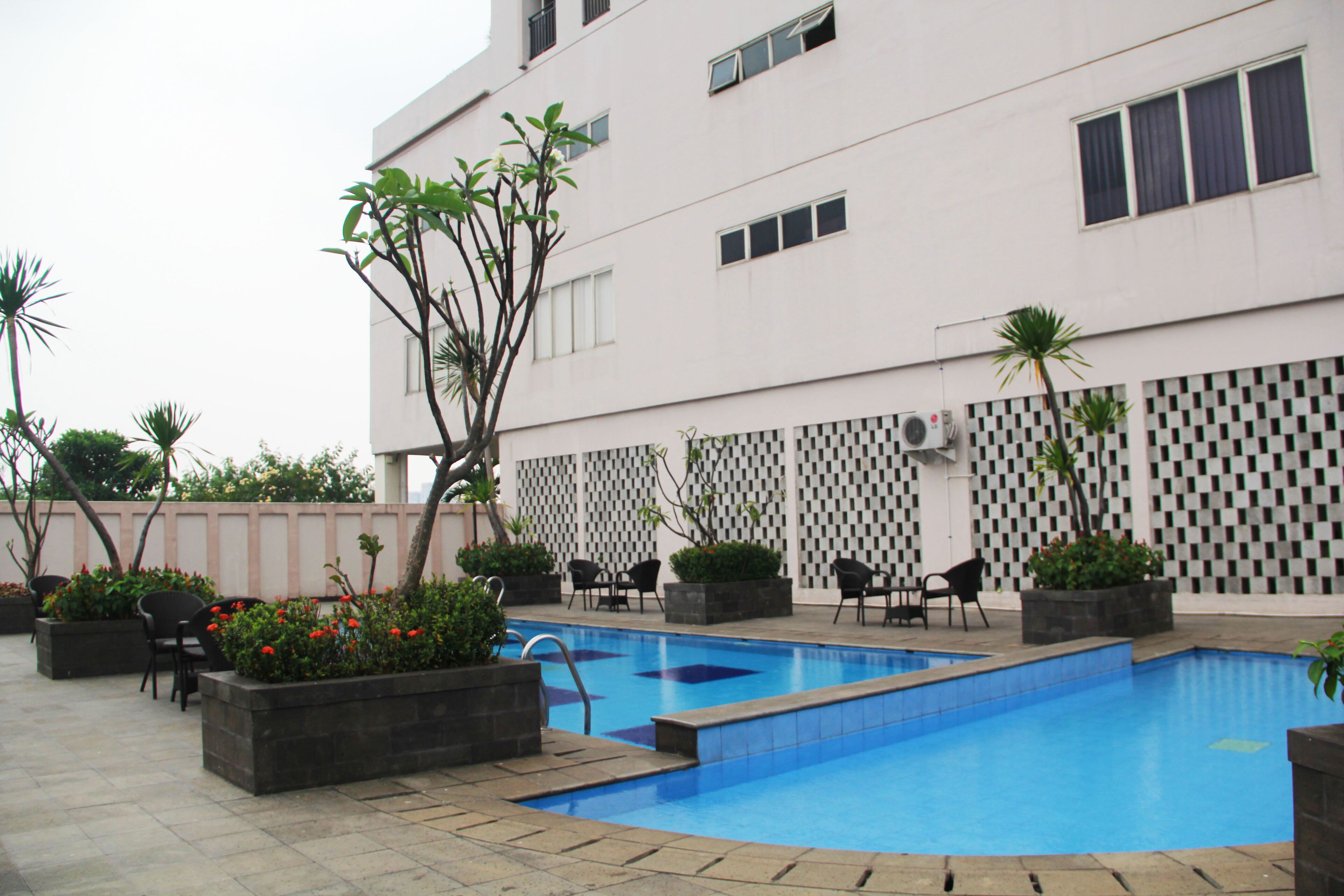 A swimming pool area with multiple seating arrangements and potted plants.