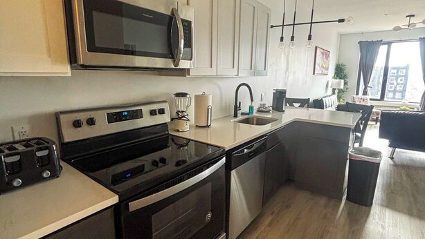 A modern kitchen with stainless steel appliances, a central island, and a dining area with a view.