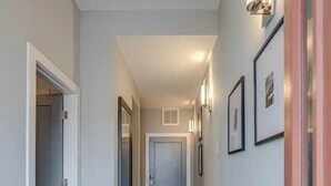 A hallway with a polished floor, framed pictures on the walls, and a door at the end.