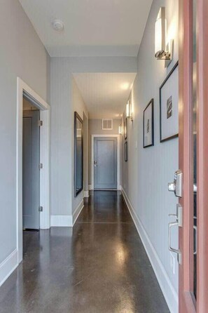 A hallway with a polished floor, framed pictures on the walls, and a door at the end.