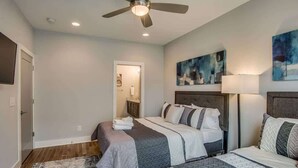 A bedroom with two beds, a ceiling fan, and artwork on the walls.