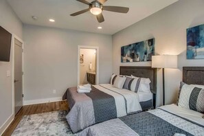 A bedroom with two beds, a ceiling fan, and artwork on the walls.