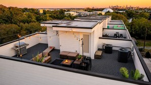 A rooftop terrace with outdoor seating, a grill, and string lights.