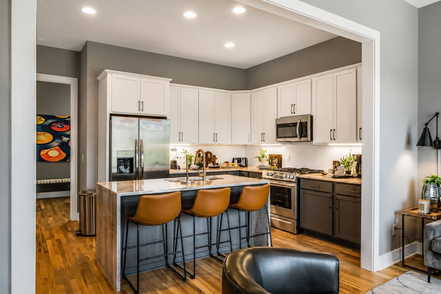 A modern kitchen with white cabinets, stainless steel appliances, and a bar area with stools.