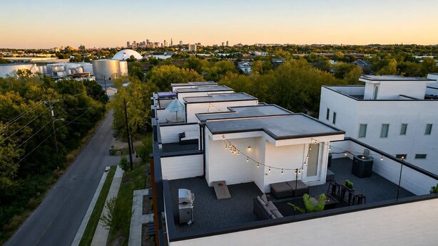 A rooftop terrace with a seating area, a water tank, and a view of a city skyline.