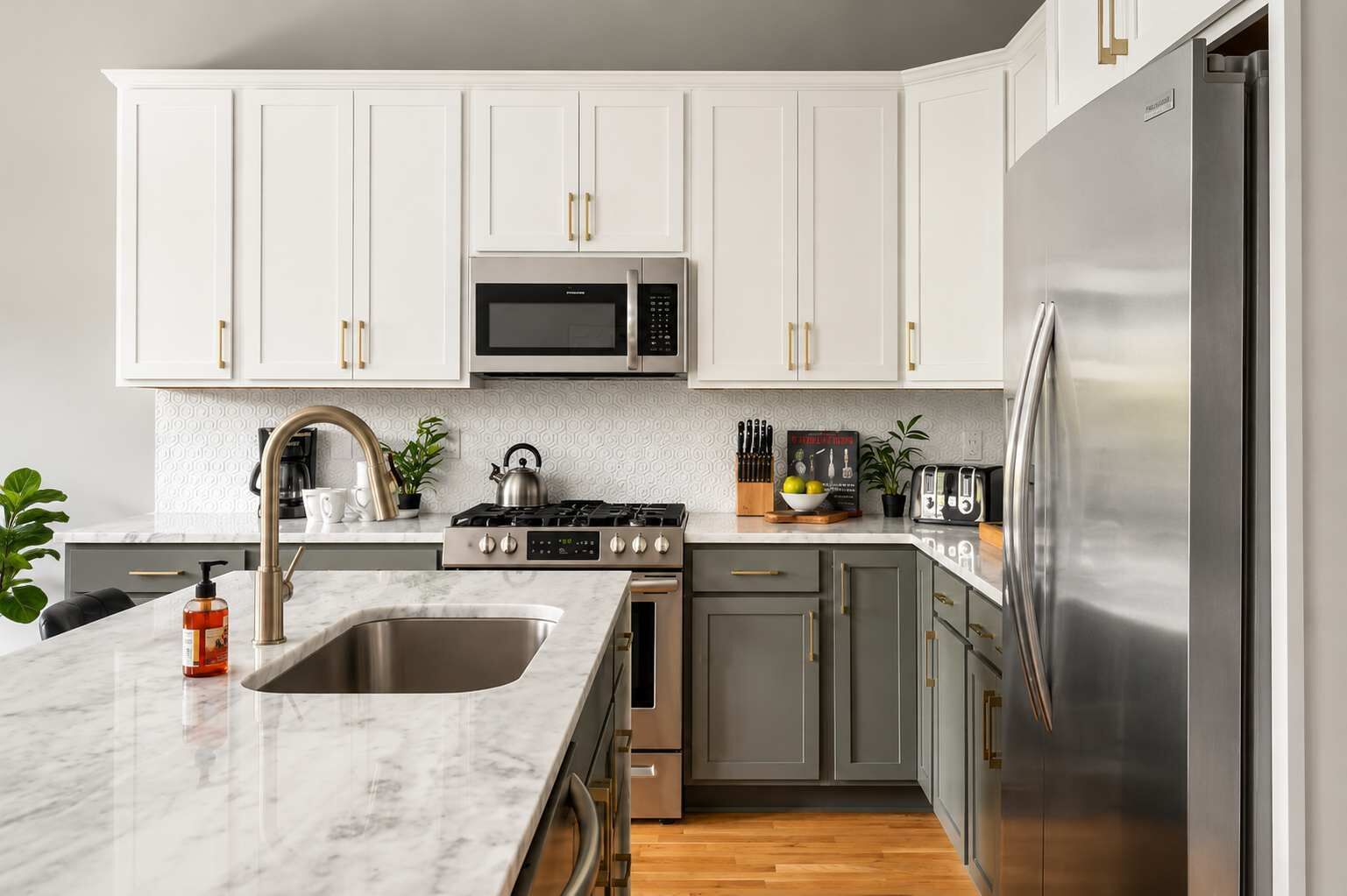 Una cocina moderna con armarios blancos, electrodomésticos de acero inoxidable y encimera de mármol.