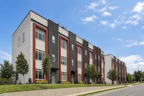 A multi-story residential building with a modern architectural design, featuring a combination of brick and siding exteriors, and a series of windows aligned vertically. - Luxury Nashville Rooftop Retreat • Sleeps 12 (Nashville)