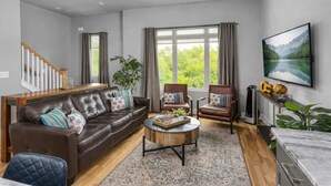 A modern living room with a leather sofa, armchairs, a coffee table, and a TV. - Luxury Nashville Rooftop Retreat • Sleeps 12 (Nashville)