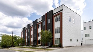 Un immeuble résidentiel à plusieurs étages, doté d’un design moderne, avec une combinaison de briques et de revêtements extérieurs, et un toit plat.