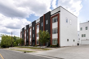 A multi-story residential building with a modern design, featuring a combination of brick and siding exteriors, and a flat roof. - Gorgeous Nashville Retreat • Skyline Rooftop (Nashville)
