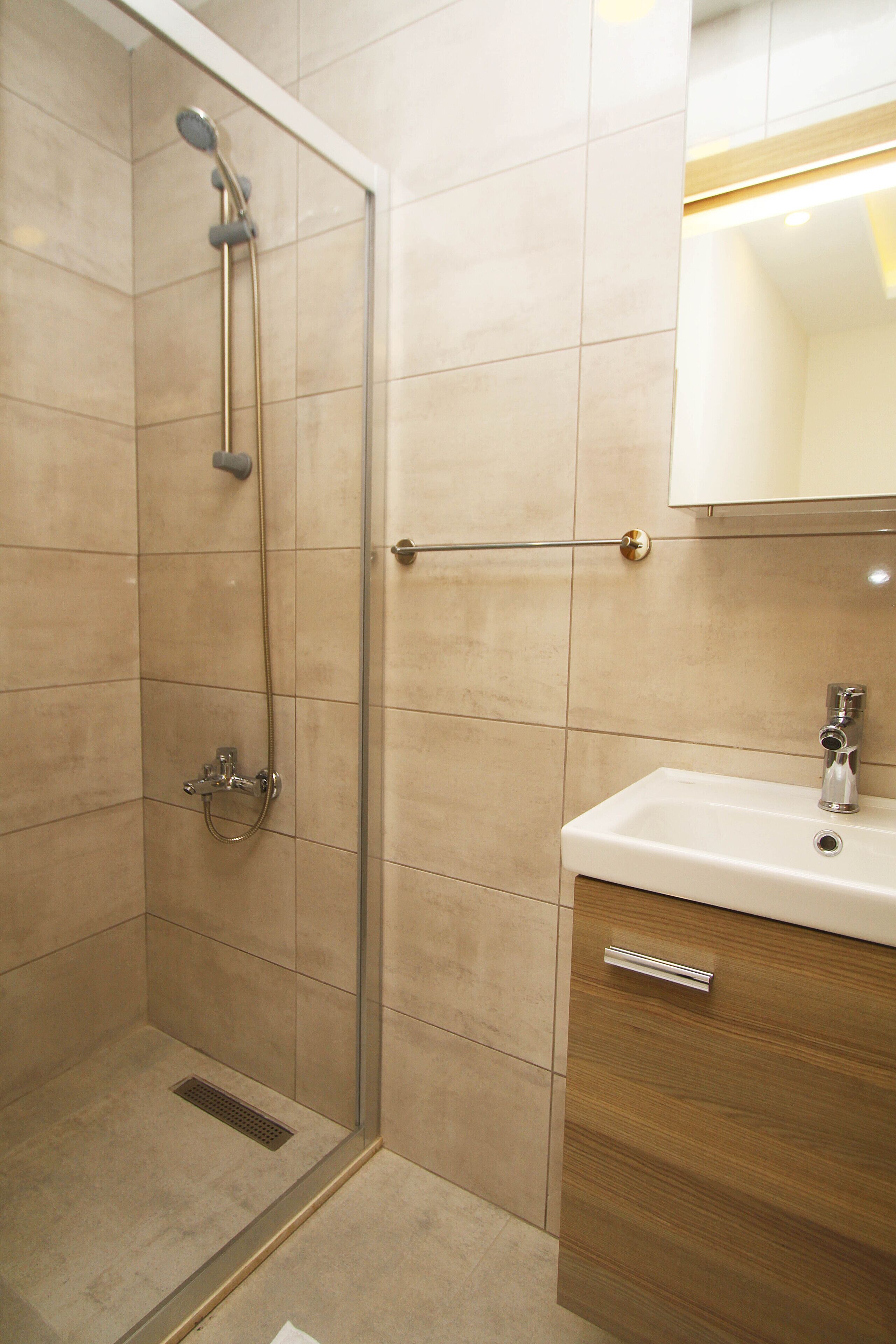 A bathroom with a shower, sink, and mirror.