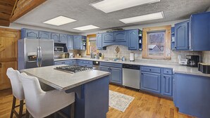 Eine Küche mit blauen Schränken, einem Edelstahlkühlschrank, einer Mikrowelle und einer Kaffeemaschine.