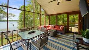 Eine großzügige Terrasse mit einem Glastisch und Stühlen, einem roten Sofa und einem Deckenventilator.
