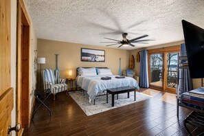 A bedroom with a bed, a chair, a desk, a television, and a view of the outdoors. - Lakefront Family Retreat • Dock • Hot Tub & Games (Cadiz)