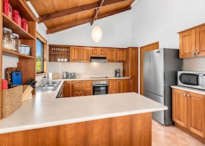 A modern kitchen with wooden cabinets, stainless steel appliances, and a large island.