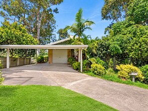 A residential property with a covered garage, a paved driveway, and a well-maintained lawn.