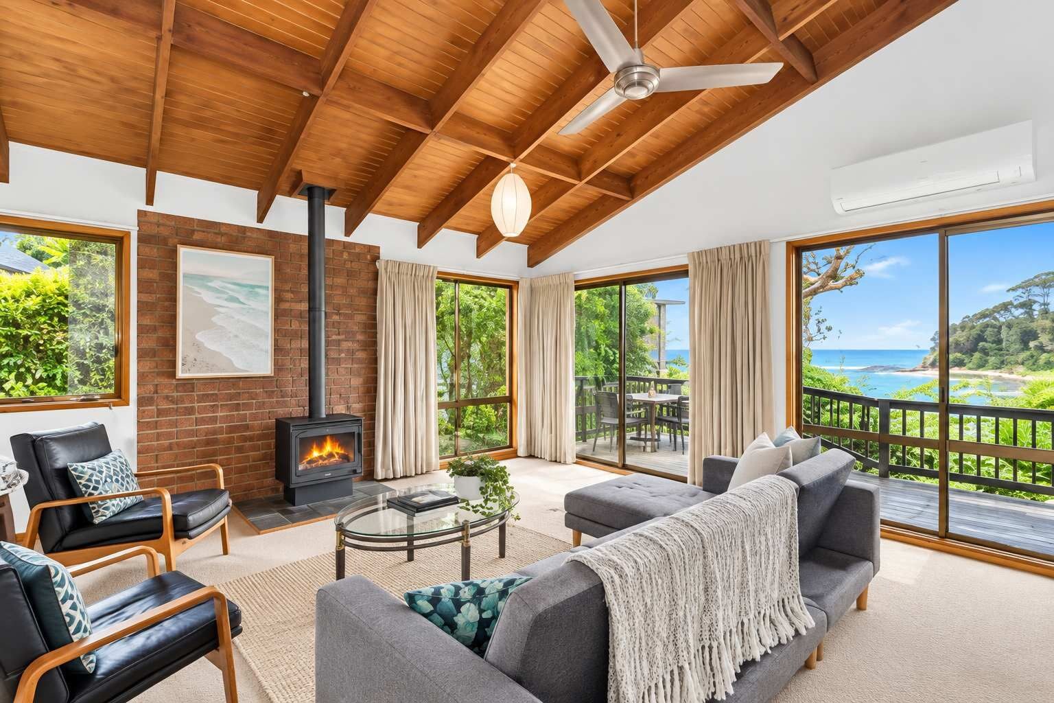 A spacious living room with a fireplace, large windows, and a view of the outdoors.