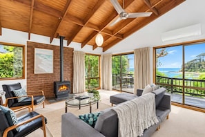A spacious living room with a fireplace, large windows, and a view of the outdoors.