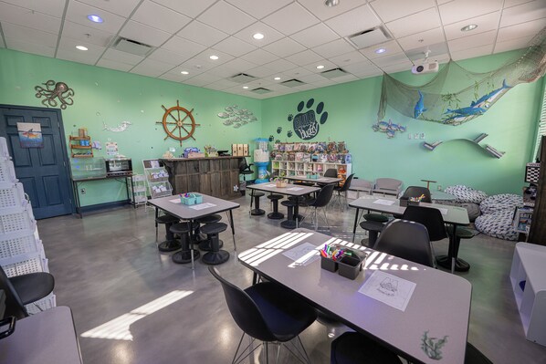 A classroom with tables, chairs, a projector, and educational materials.