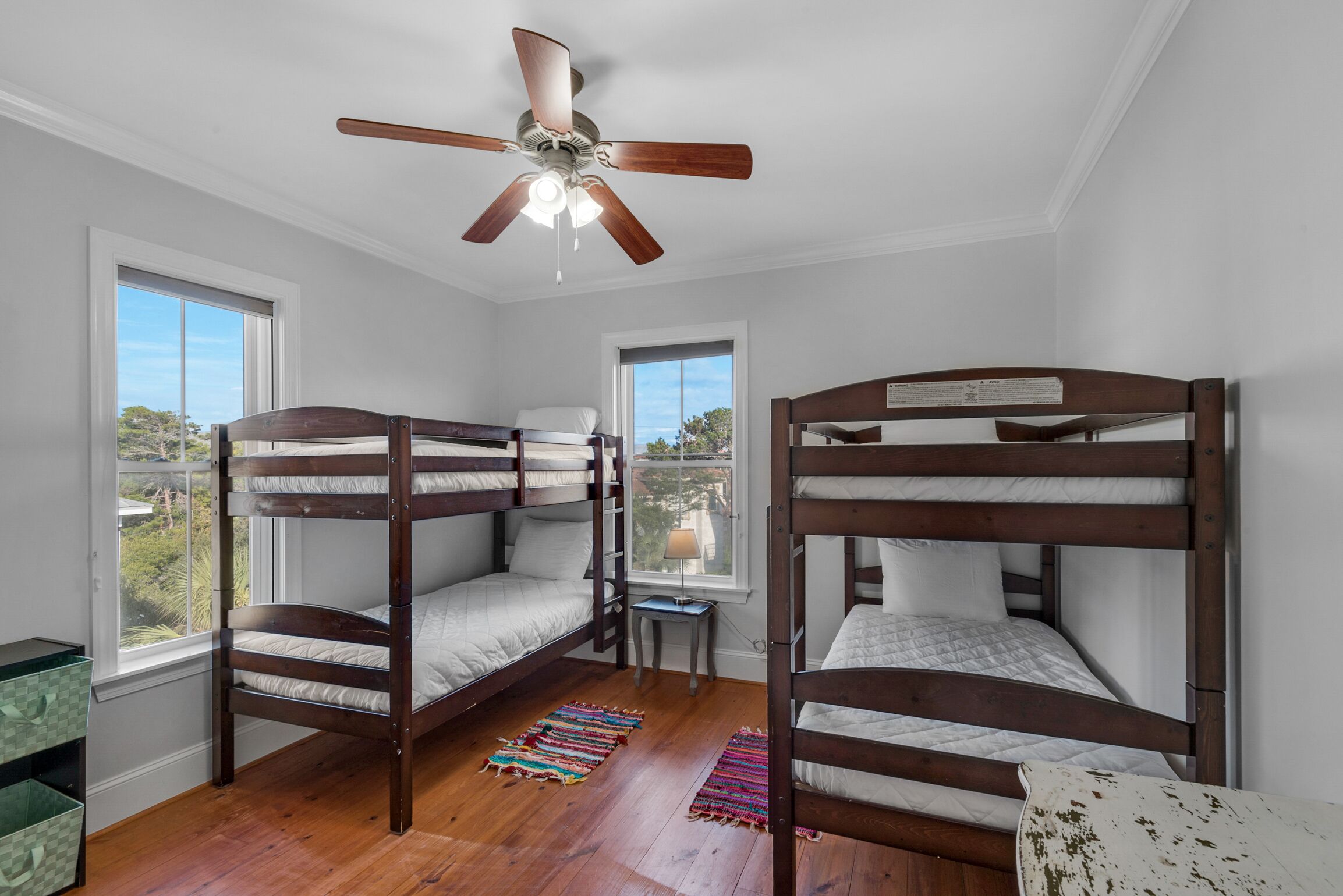 A room with bunk beds, a ceiling fan, and a view of the outdoors through a window.
