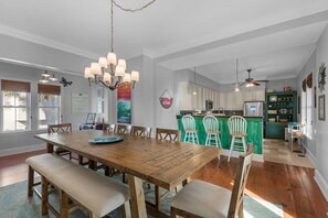 A spacious dining area with a wooden table and benches, a kitchen with green cabinets, and a ceiling fan. - ☀️Private Pool-Pet Friendly-30A-Blue Mountain Breeze (Santa Rosa Beach)